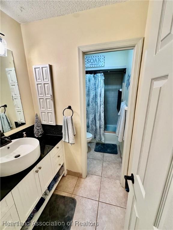 full bathroom with shower / tub combo, vanity, a textured ceiling, tile patterned floors, and toilet