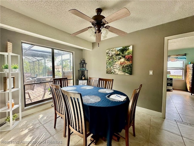 tiled dining space with ceiling fan and a textured ceiling