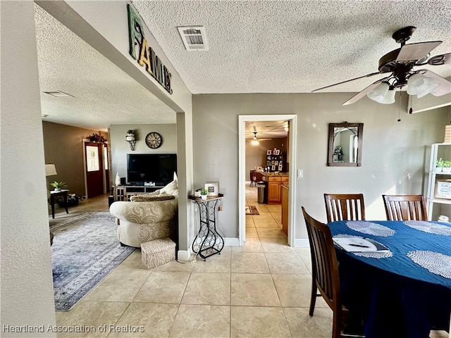 tiled dining space with ceiling fan and a textured ceiling