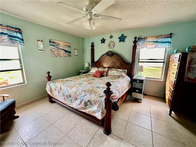 tiled bedroom featuring ceiling fan, multiple windows, and a textured ceiling