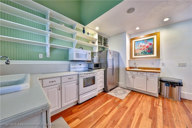 kitchen with white cabinetry, sink, stainless steel appliances, and light wood-type flooring