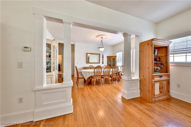 dining space featuring ornate columns and light wood-type flooring