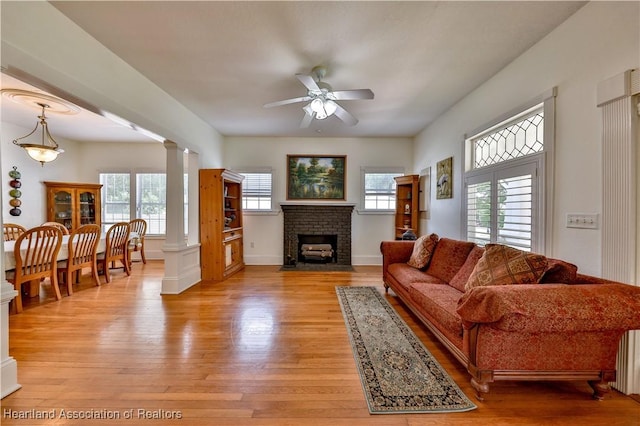 living room with light hardwood / wood-style flooring, ornate columns, ceiling fan, and a healthy amount of sunlight