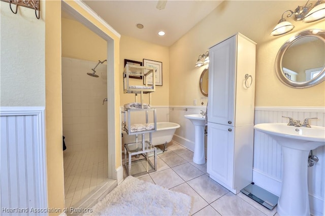 bathroom featuring tile patterned flooring, a tile shower, and sink