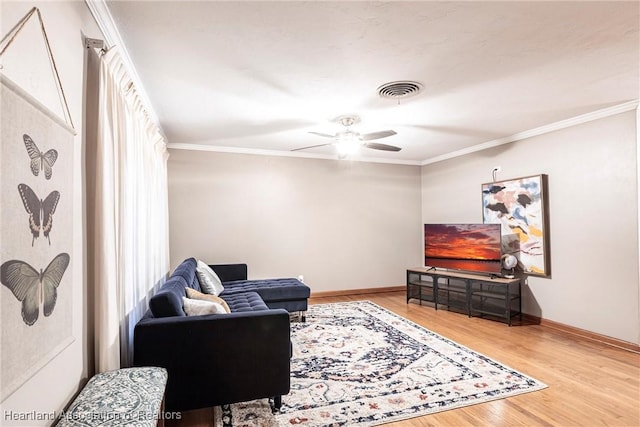 living room featuring ornamental molding, visible vents, baseboards, and wood finished floors