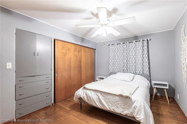 bedroom featuring crown molding, a closet, a ceiling fan, wood finished floors, and baseboards