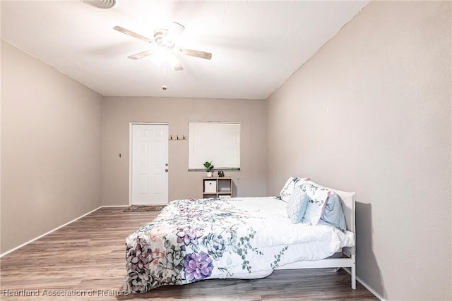 bedroom featuring ceiling fan, baseboards, and wood finished floors