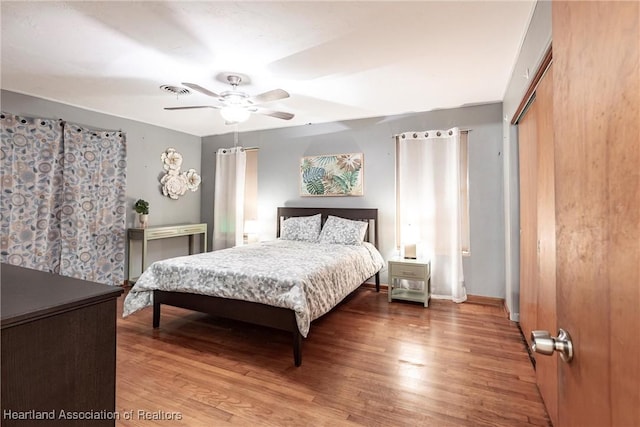 bedroom with a ceiling fan, a closet, baseboards, and wood finished floors