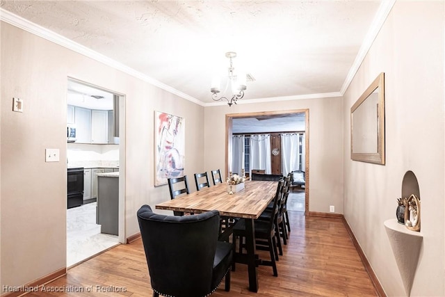 dining room with ornamental molding, baseboards, light wood finished floors, and an inviting chandelier