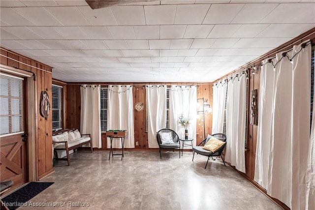 living area featuring concrete flooring and wooden walls