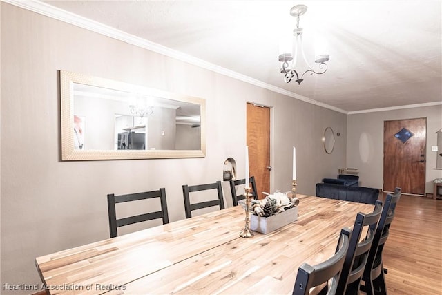 dining space with ornamental molding, a notable chandelier, and wood finished floors