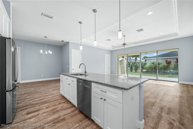 35151 Daily Dr, Sebring, FL 33872 - kitchen with appliances with stainless steel finishes, ceiling fan with notable chandelier, a tray ceiling, sink, and white cabinets