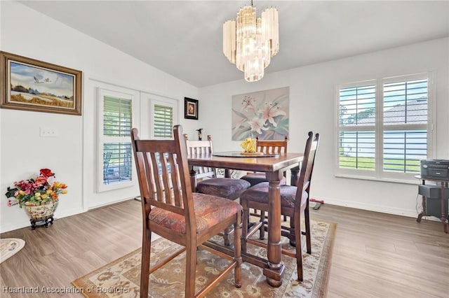 dining space featuring baseboards, a chandelier, and wood finished floors