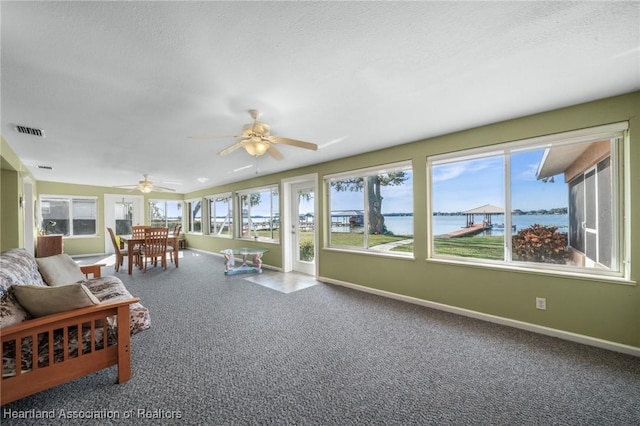 sunroom featuring ceiling fan and a water view