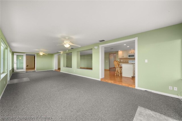 carpeted spare room featuring baseboards and ceiling fan