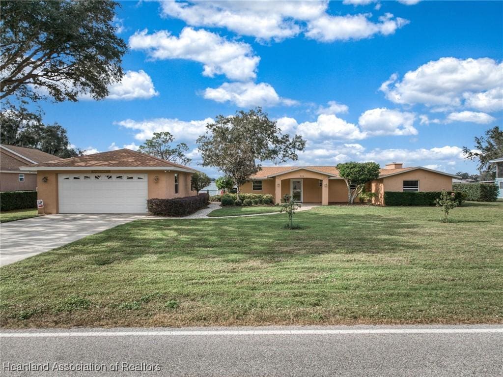 single story home featuring stucco siding, a garage, driveway, and a front lawn