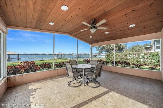 sunroom / solarium featuring ceiling fan, vaulted ceiling, wood ceiling, and a water view