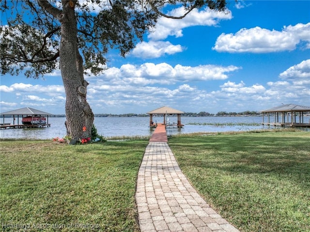 dock area with a lawn, a water view, and a gazebo