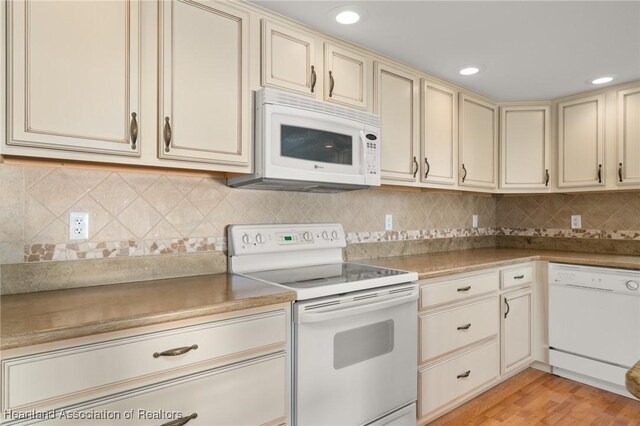 kitchen with cream cabinetry, white appliances, light wood-style floors, backsplash, and recessed lighting