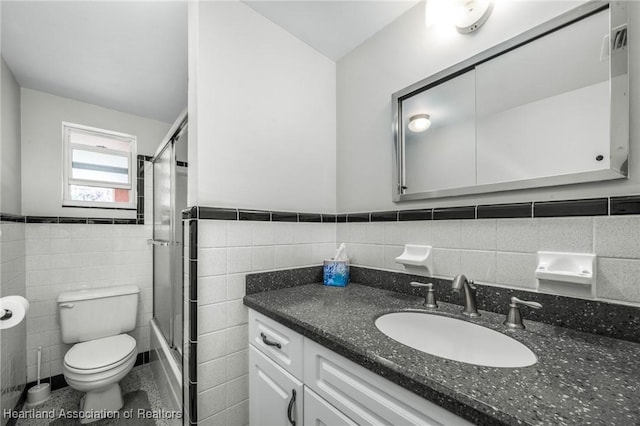 bathroom with toilet, vanity, and tile walls