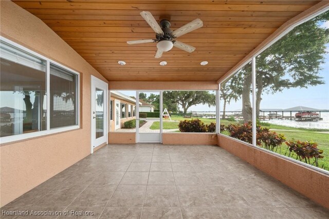 unfurnished sunroom with a ceiling fan and a water view
