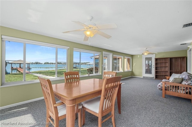 sunroom with ceiling fan and a water view