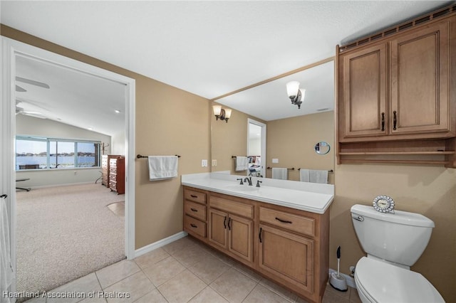 bathroom with toilet, vaulted ceiling, tile patterned flooring, ceiling fan, and vanity