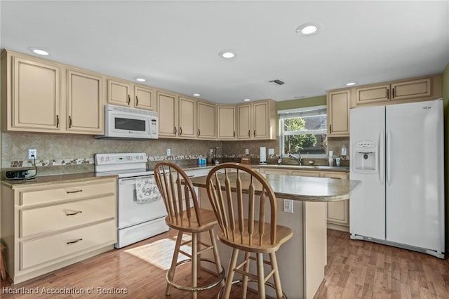 kitchen with white appliances, a center island, light hardwood / wood-style floors, decorative backsplash, and a kitchen breakfast bar