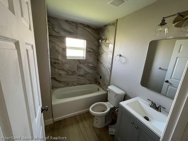 full bathroom with vanity, toilet, tiled shower / bath, and hardwood / wood-style flooring