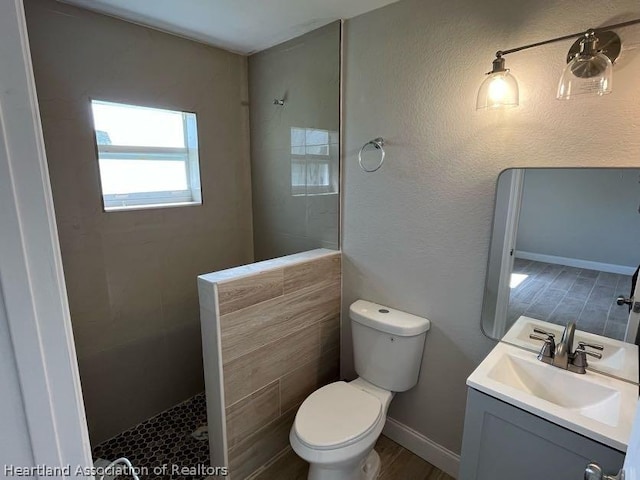 bathroom featuring hardwood / wood-style floors, vanity, toilet, and a tile shower