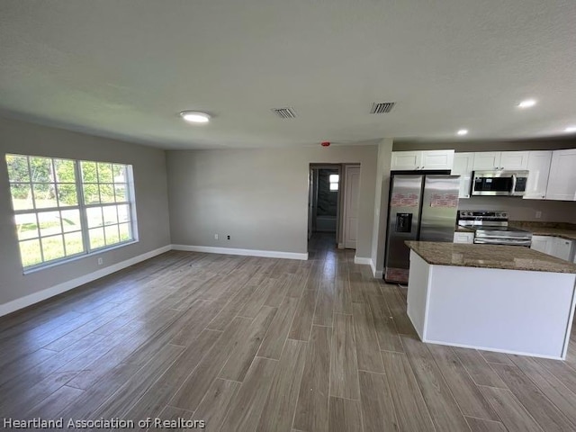 kitchen featuring white cabinets, appliances with stainless steel finishes, light hardwood / wood-style flooring, and dark stone countertops