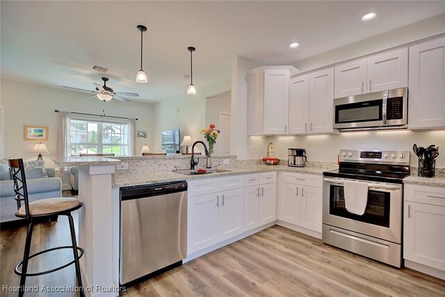 kitchen with kitchen peninsula, white cabinetry, sink, and appliances with stainless steel finishes