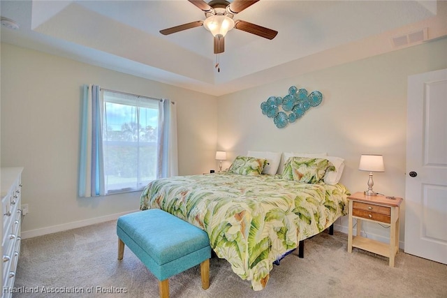 bedroom featuring a raised ceiling, ceiling fan, and light carpet