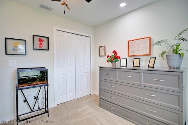 bedroom with ceiling fan, light colored carpet, and a closet