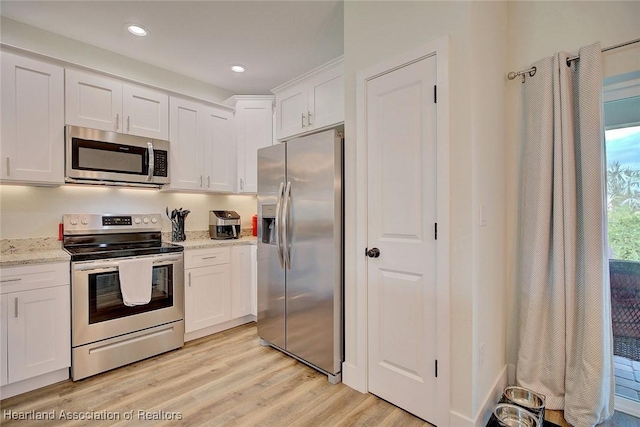 kitchen with white cabinetry, light hardwood / wood-style flooring, light stone countertops, and appliances with stainless steel finishes