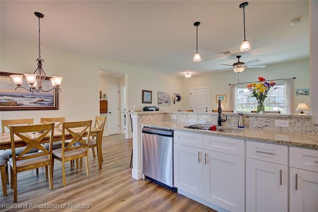 kitchen with ceiling fan with notable chandelier, sink, stainless steel dishwasher, light stone countertops, and white cabinetry