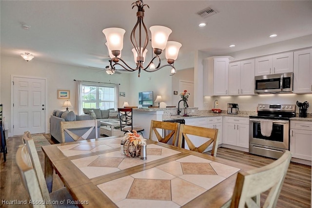 dining space featuring ceiling fan with notable chandelier and sink