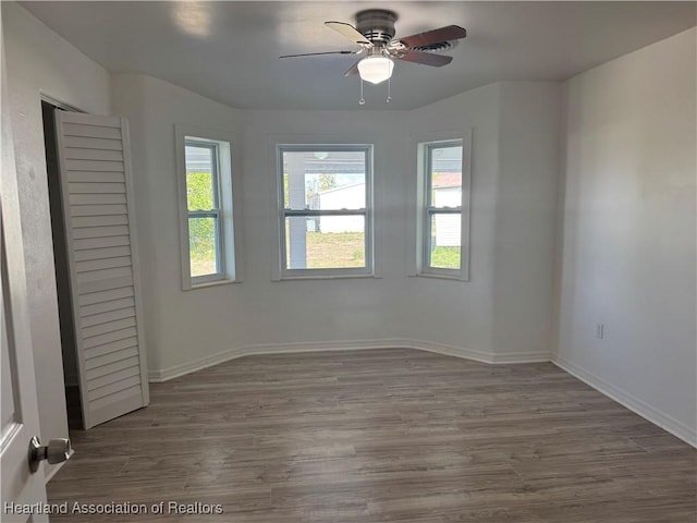 empty room with baseboards, ceiling fan, and wood finished floors