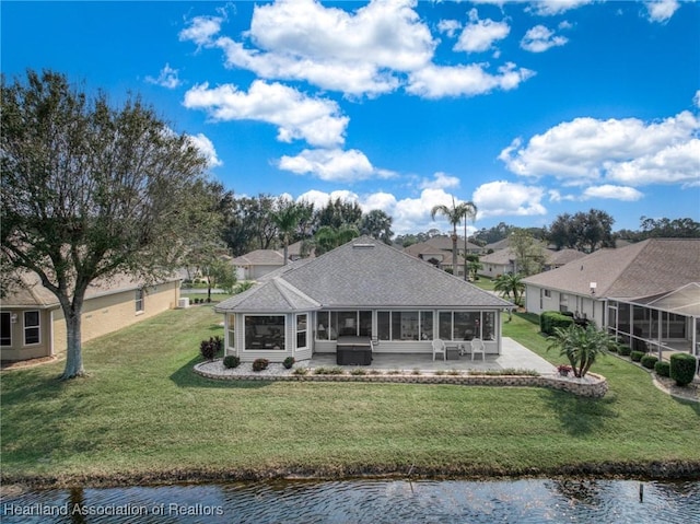 rear view of house featuring a patio area, a sunroom, a yard, and a water view