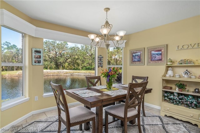 dining space featuring light tile patterned floors, a water view, and a notable chandelier