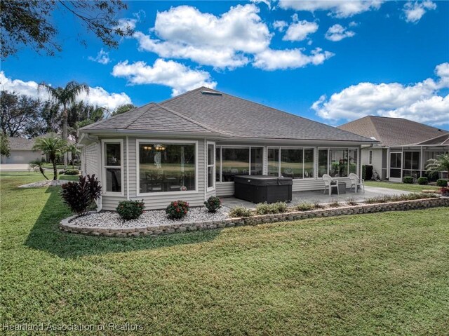 rear view of property with a yard, a hot tub, and a patio area