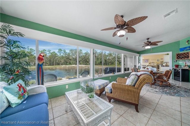 sunroom featuring a water view, a wealth of natural light, lofted ceiling, and ceiling fan