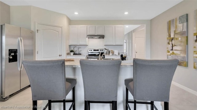 6836 Coconut Dr, Sebring, FL 33872 - kitchen with appliances with stainless steel finishes, under cabinet range hood, light countertops, a sink, and a kitchen bar