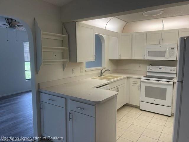 kitchen with white appliances, white cabinetry, sink, kitchen peninsula, and ceiling fan