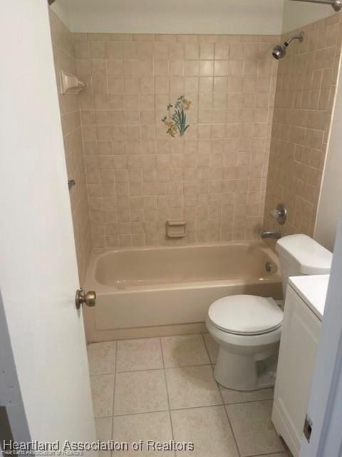 full bathroom featuring toilet, vanity, tiled shower / bath, and tile patterned flooring