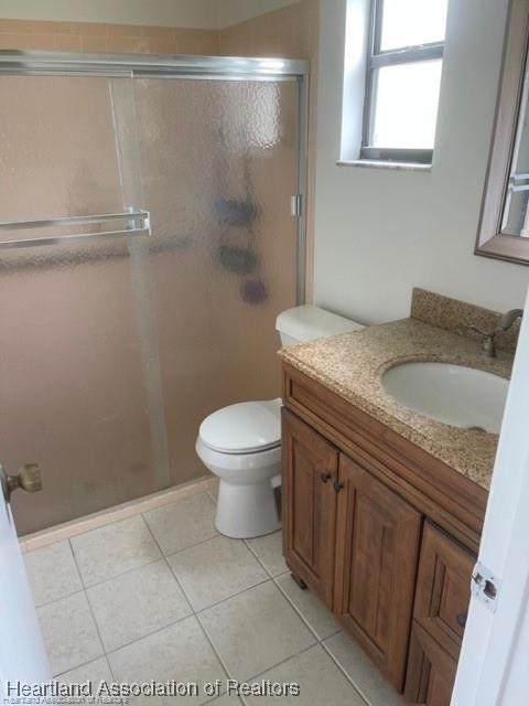 bathroom featuring a shower with door, toilet, and vanity