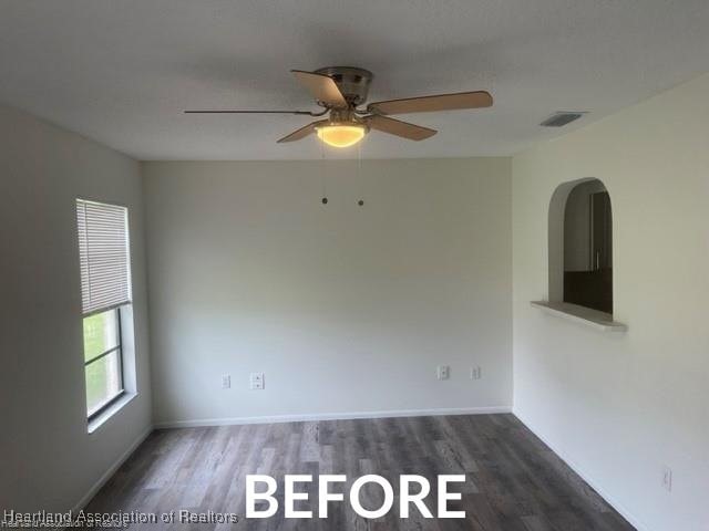 spare room with dark wood-type flooring, a ceiling fan, visible vents, and baseboards