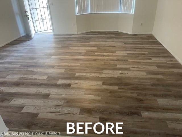 spare room featuring dark wood-type flooring and baseboards