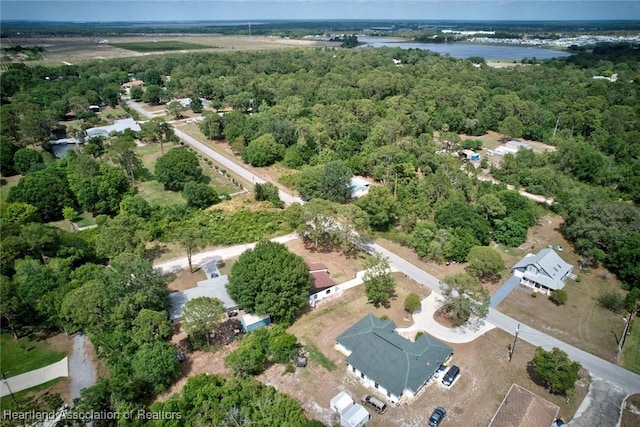 drone / aerial view featuring a wooded view and a water view
