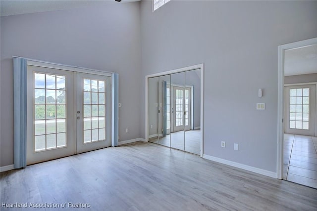 interior space with wood finished floors, french doors, a high ceiling, and baseboards